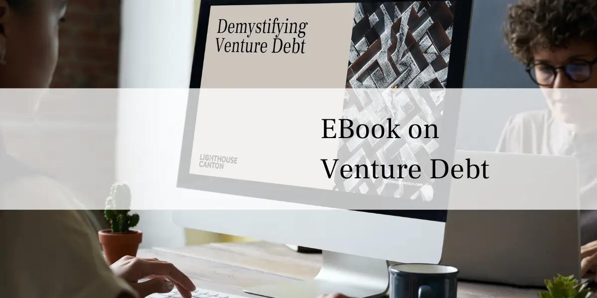 Person working on a computer displaying an eBook titled "Demystifying Venture Debt".