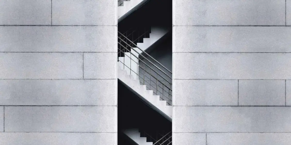 Concrete steps with a handrail, framed by a building facade.