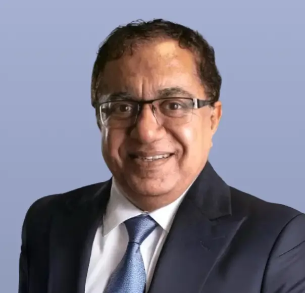 Dinesh Gogia, a man in a dark suit and glasses, smiles.