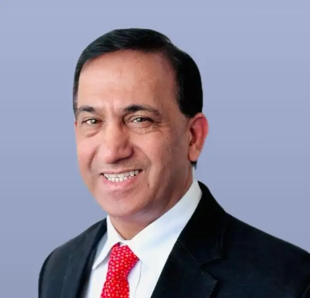Sunil Garg, a man in a dark suit and red tie, smiles.