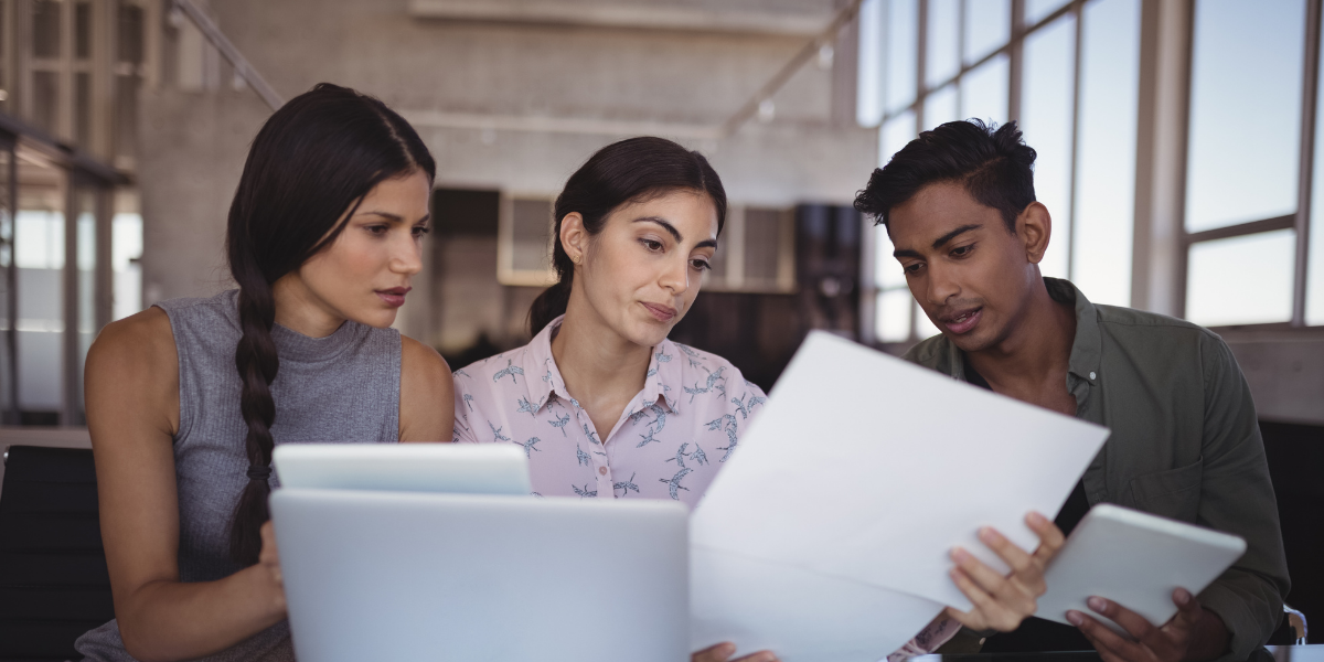 Two people review documents on a laptop and tablet.