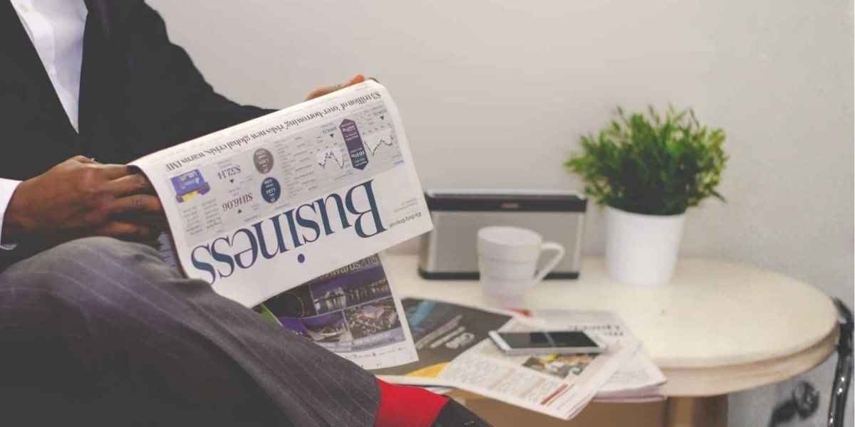 A man reads a newspaper displaying the Lighthouse Canton.