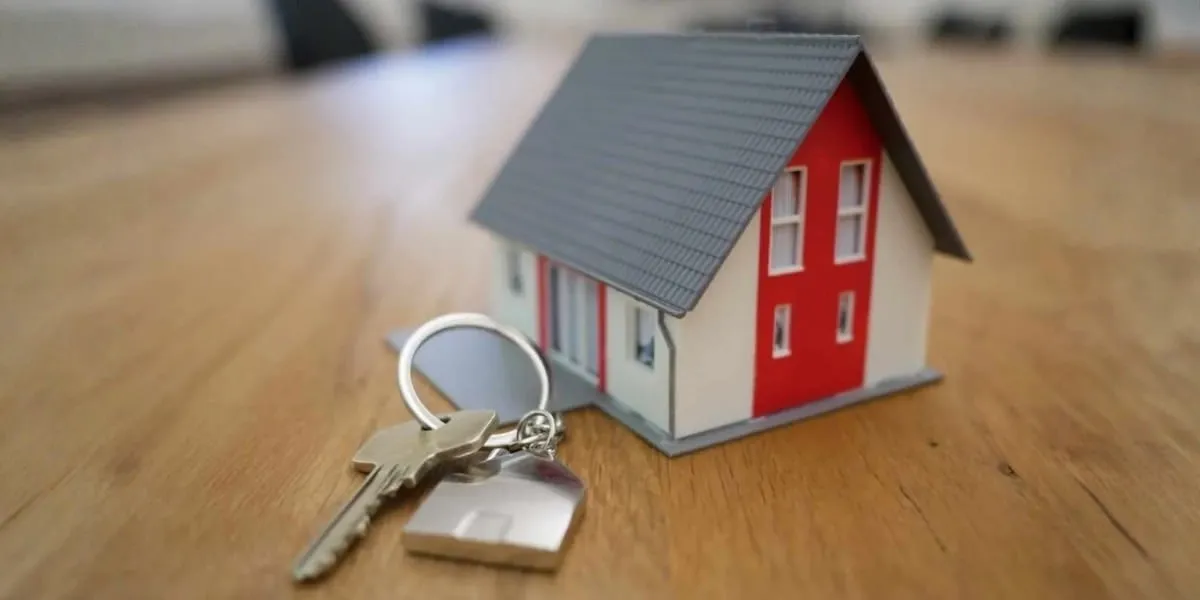 Miniature house with keys on wooden table.