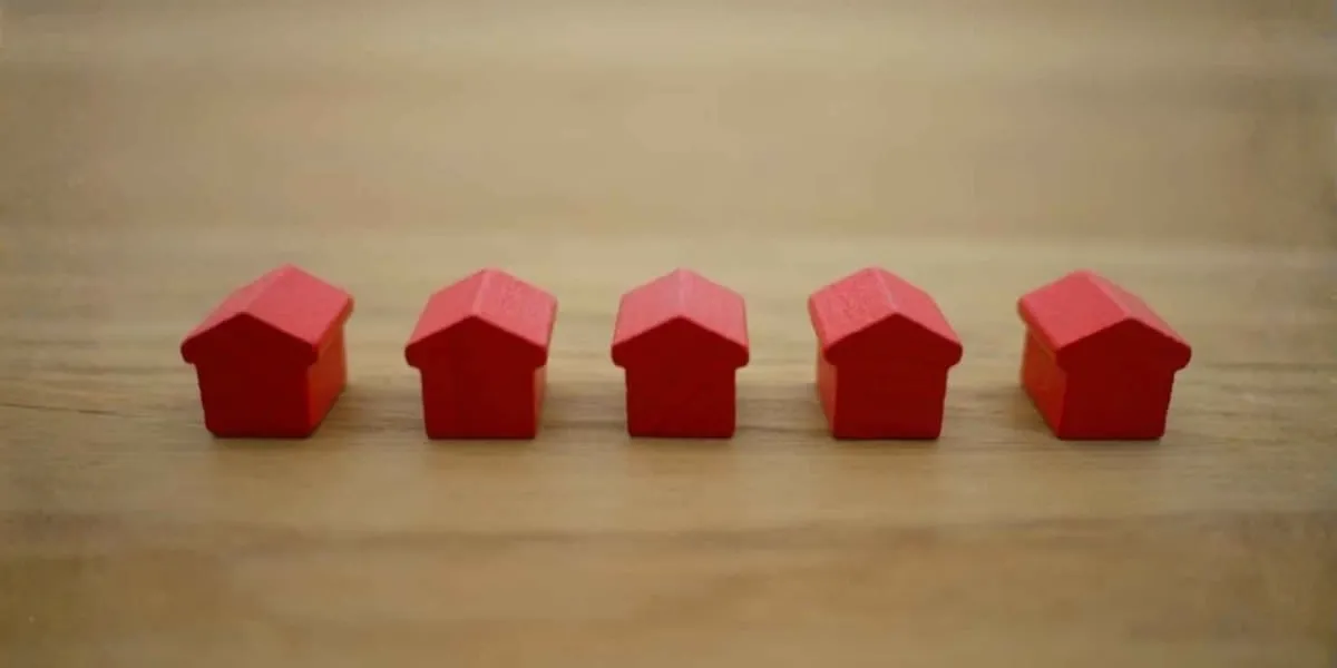 Five miniature red houses on a wooden surface.