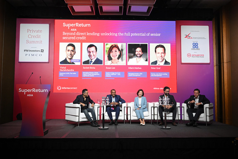 Panel of five individuals seated at a conference table during a private credit summit.