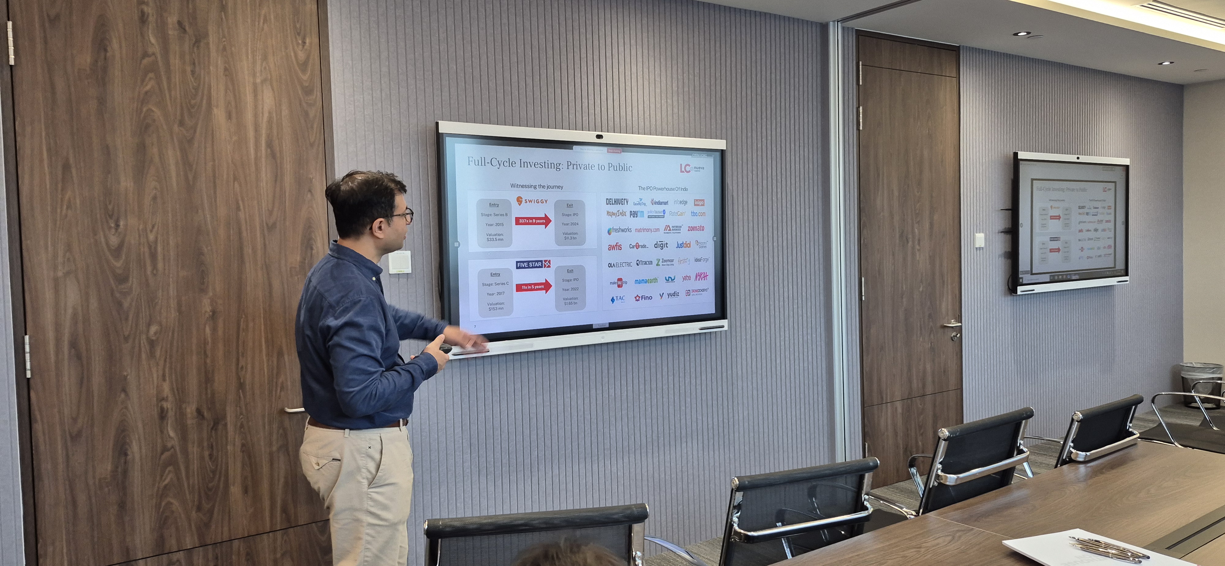 Man presenting data on a digital display showing investment performance metrics.