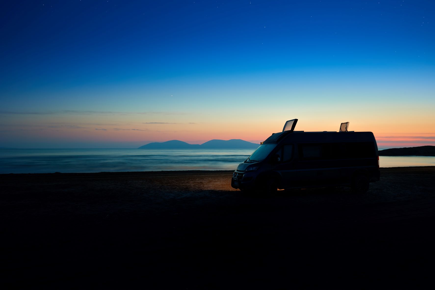 Campervan am Meer bei Sonnenuntergang