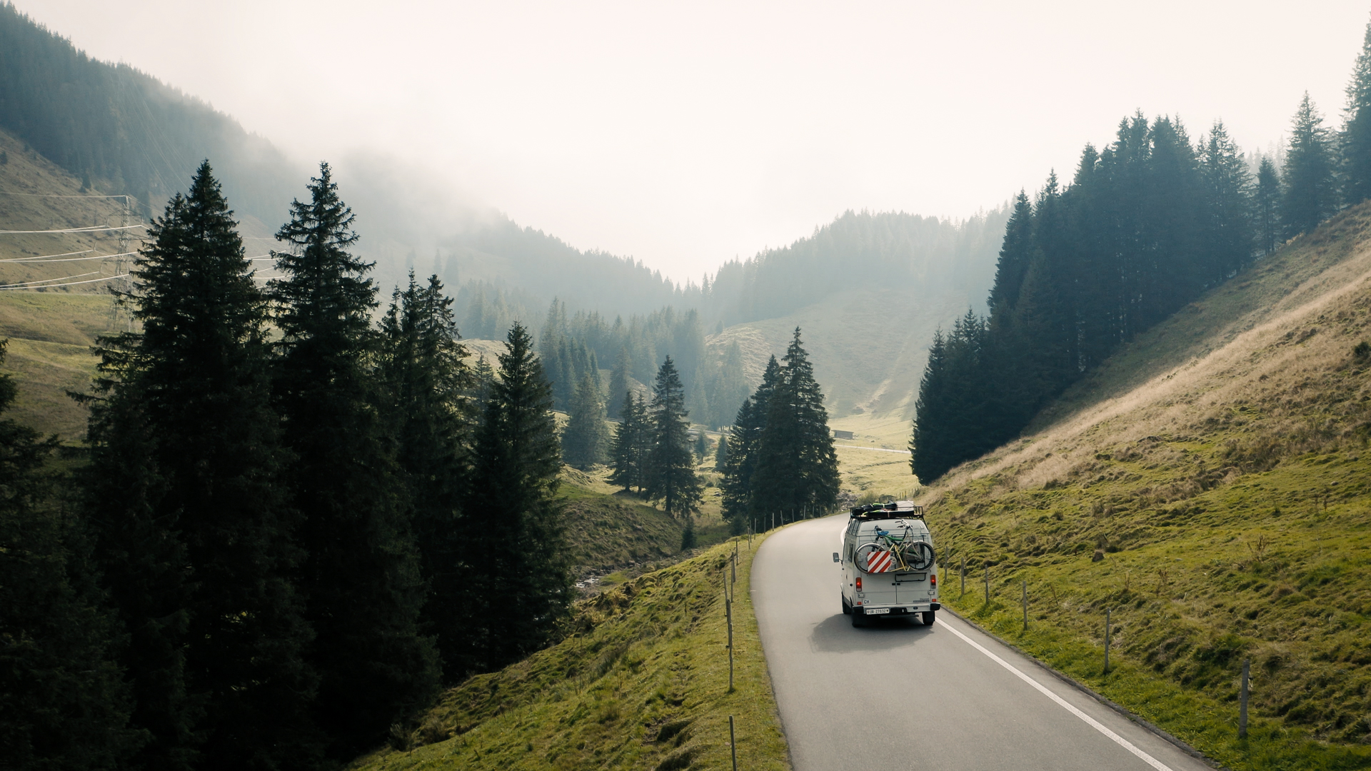 Camper with bikes on a mountain road in the fog