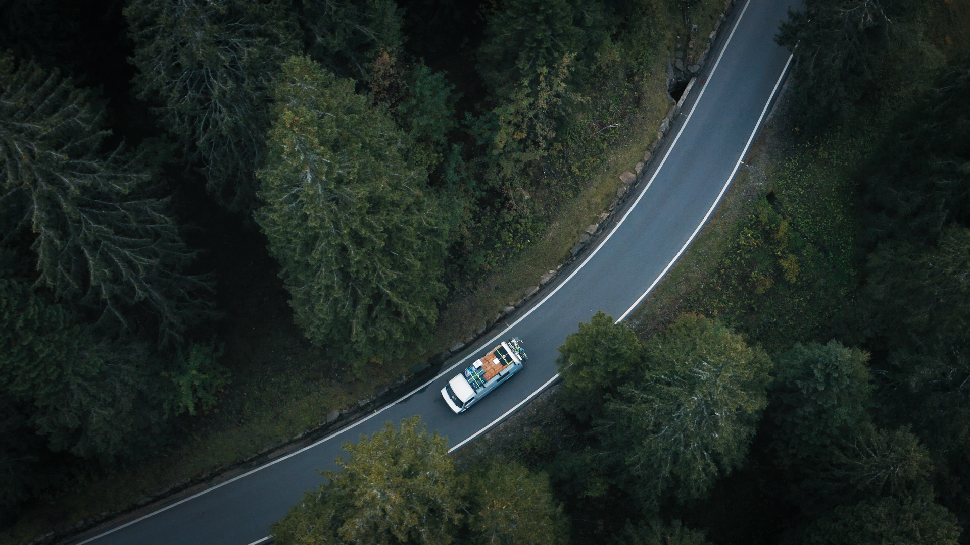 Camper with bikes on a forest road, aerial view