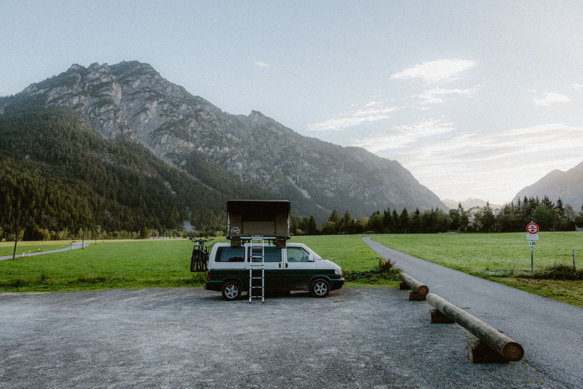 Camper auf einem Parkplatz vor Bergkulisse
