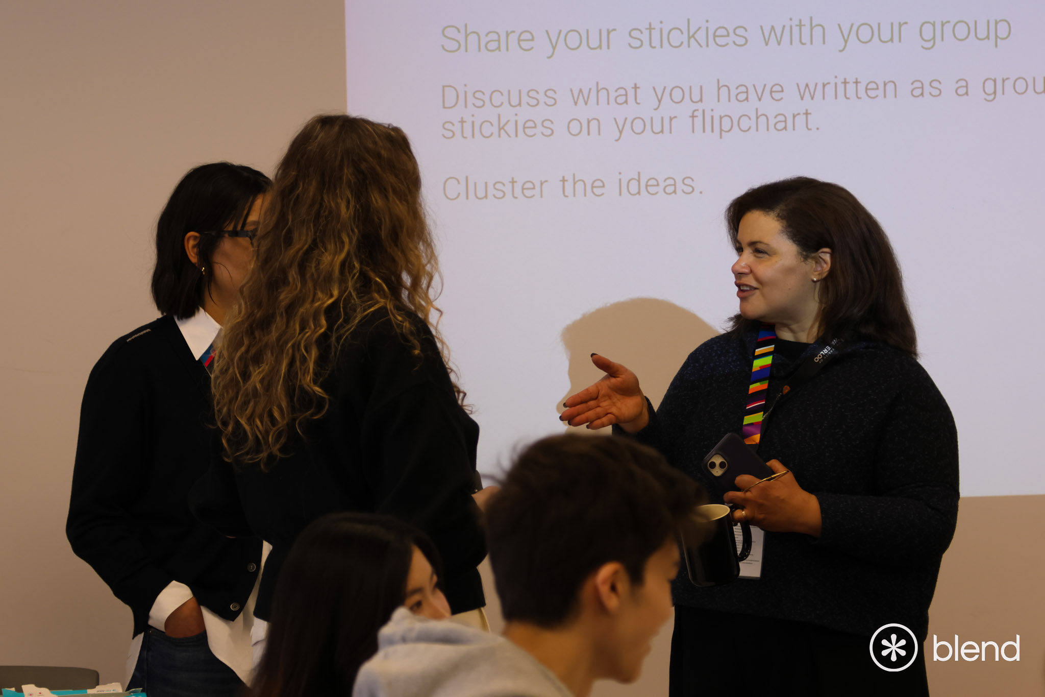 BLEND workshop presenter speaking with attendees in front of a projector