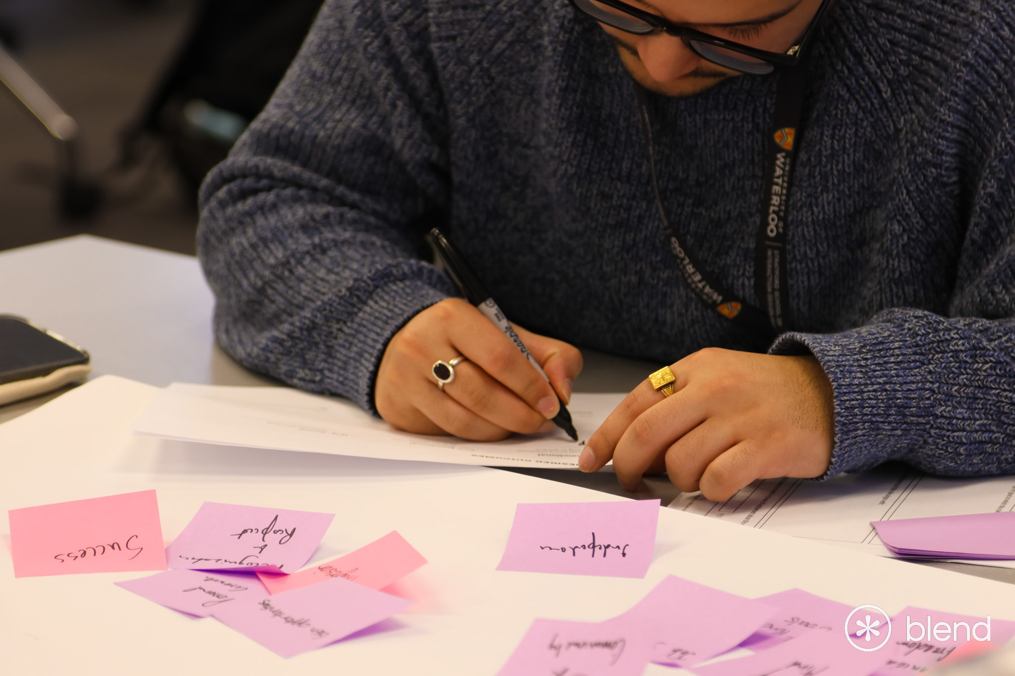 BLEND attendee writing on table with lots of pink and purple sticky notes.