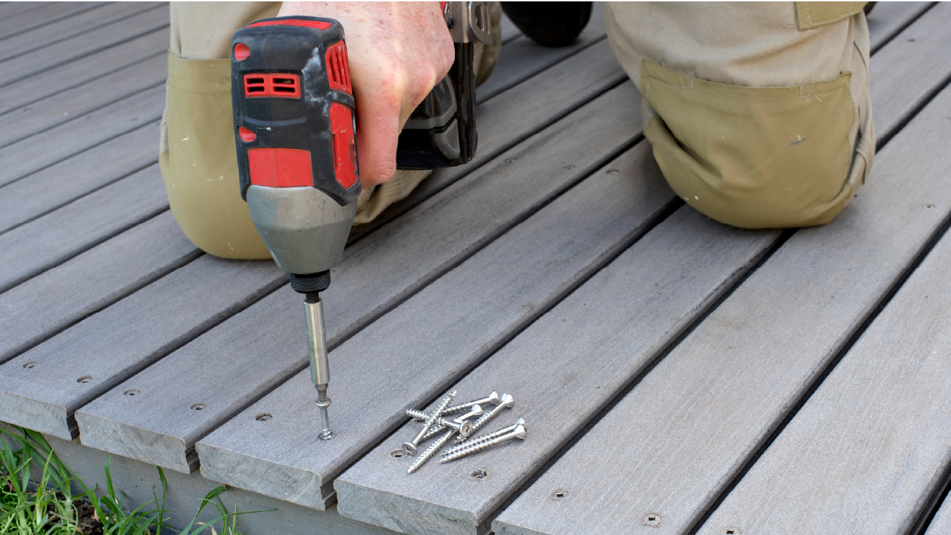 person screwing screw into deck with drill