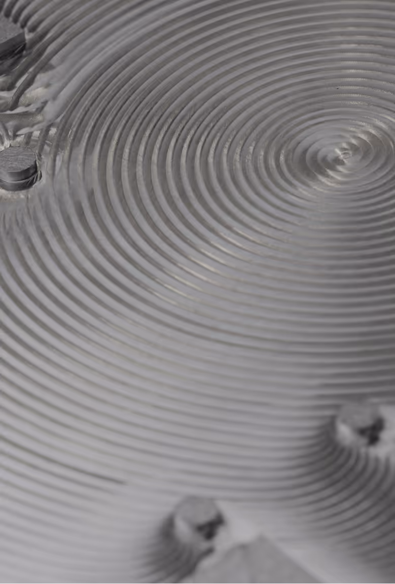 Close-up view of a metal surface with concentric circular grooves and bolt heads.