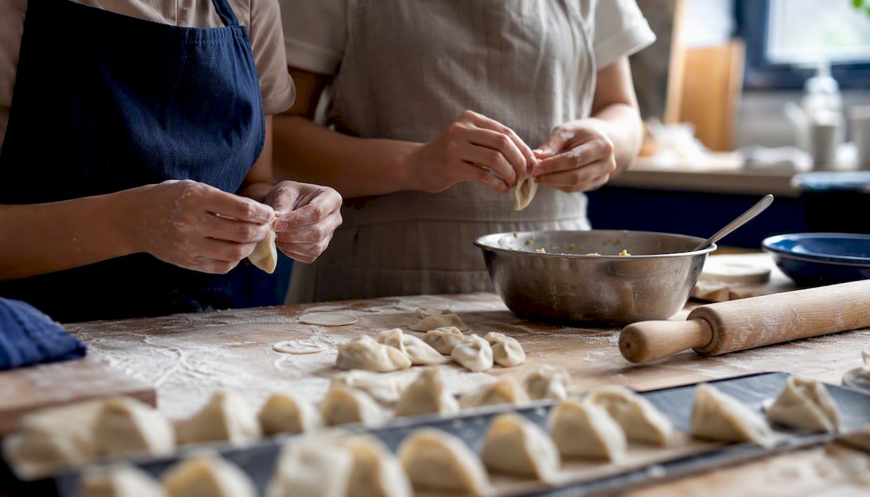 Hands folding dumplings together