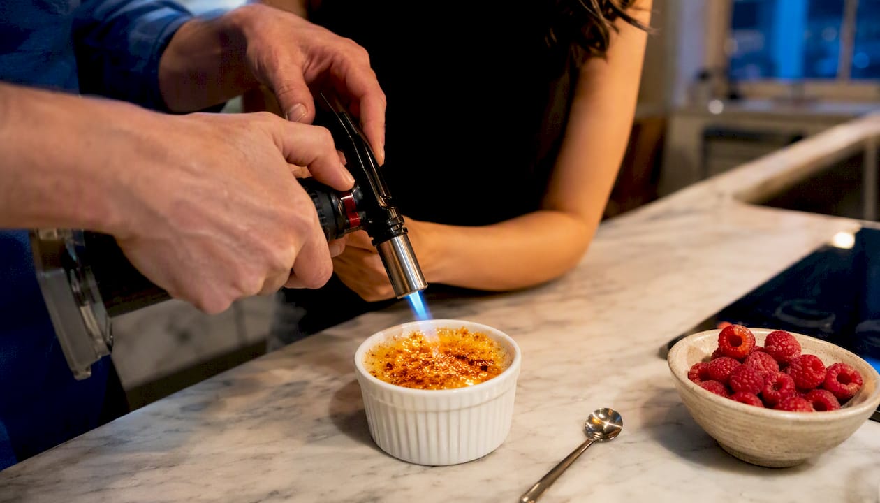 Hands torching crème brûlée sugar crust