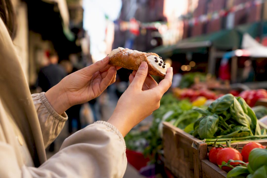 Hand holding cannoli on Boston street food tour
