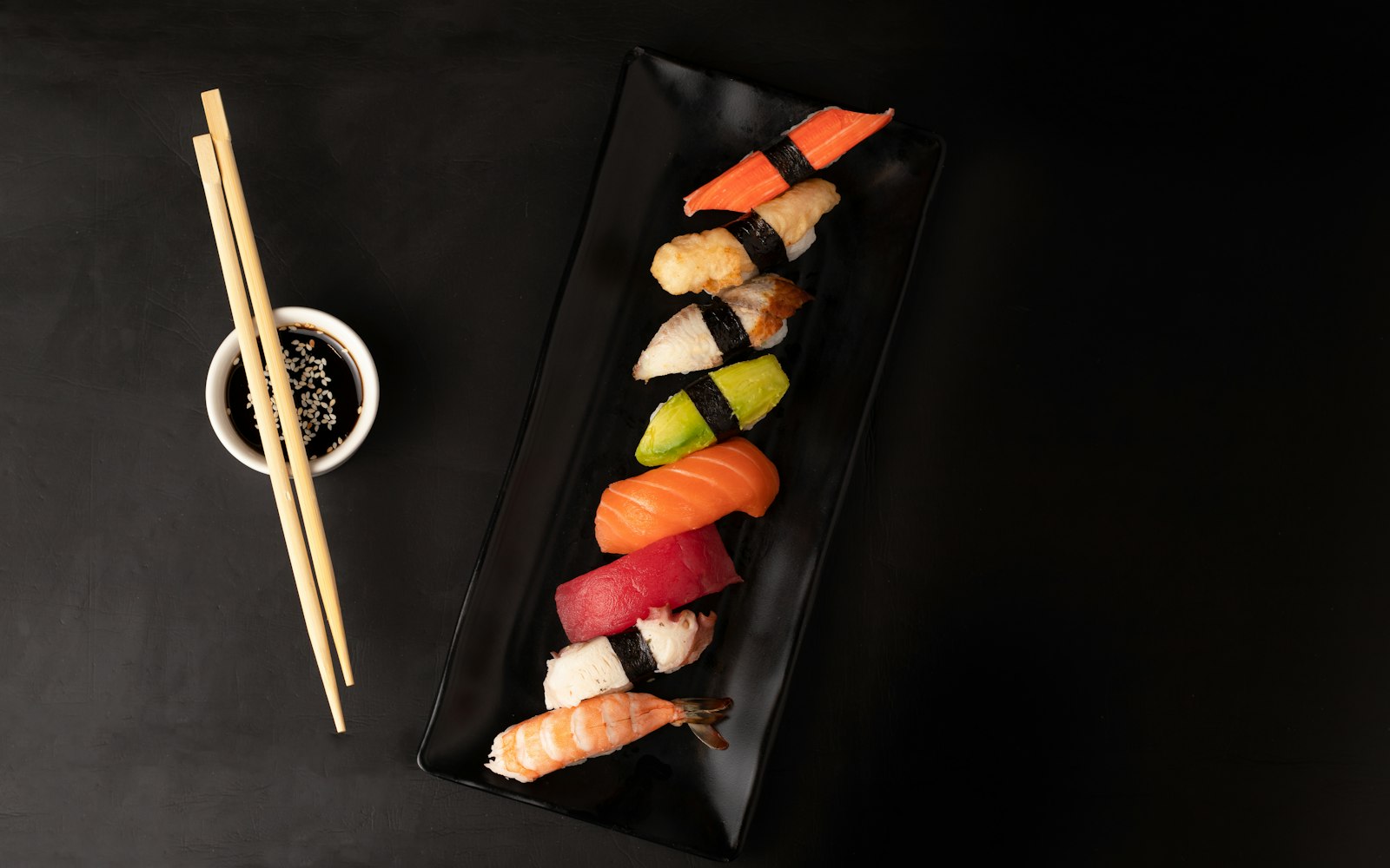 Sushi rolls and nigiri on a black plate with chopsticks from a sushi making class near West LA