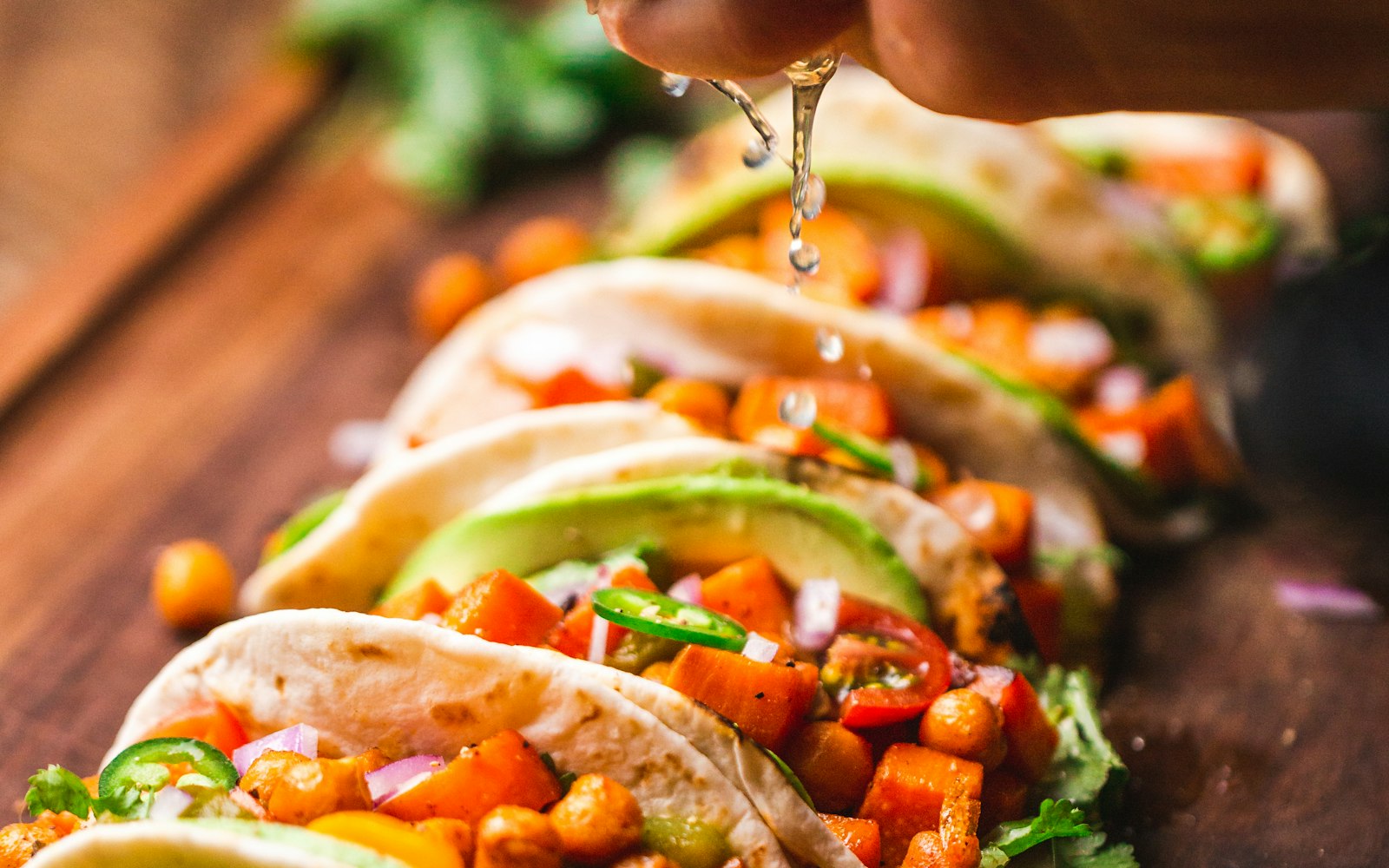Hands topping fresh tacos with lime and herbs during a Mexican cooking class near Inglewood