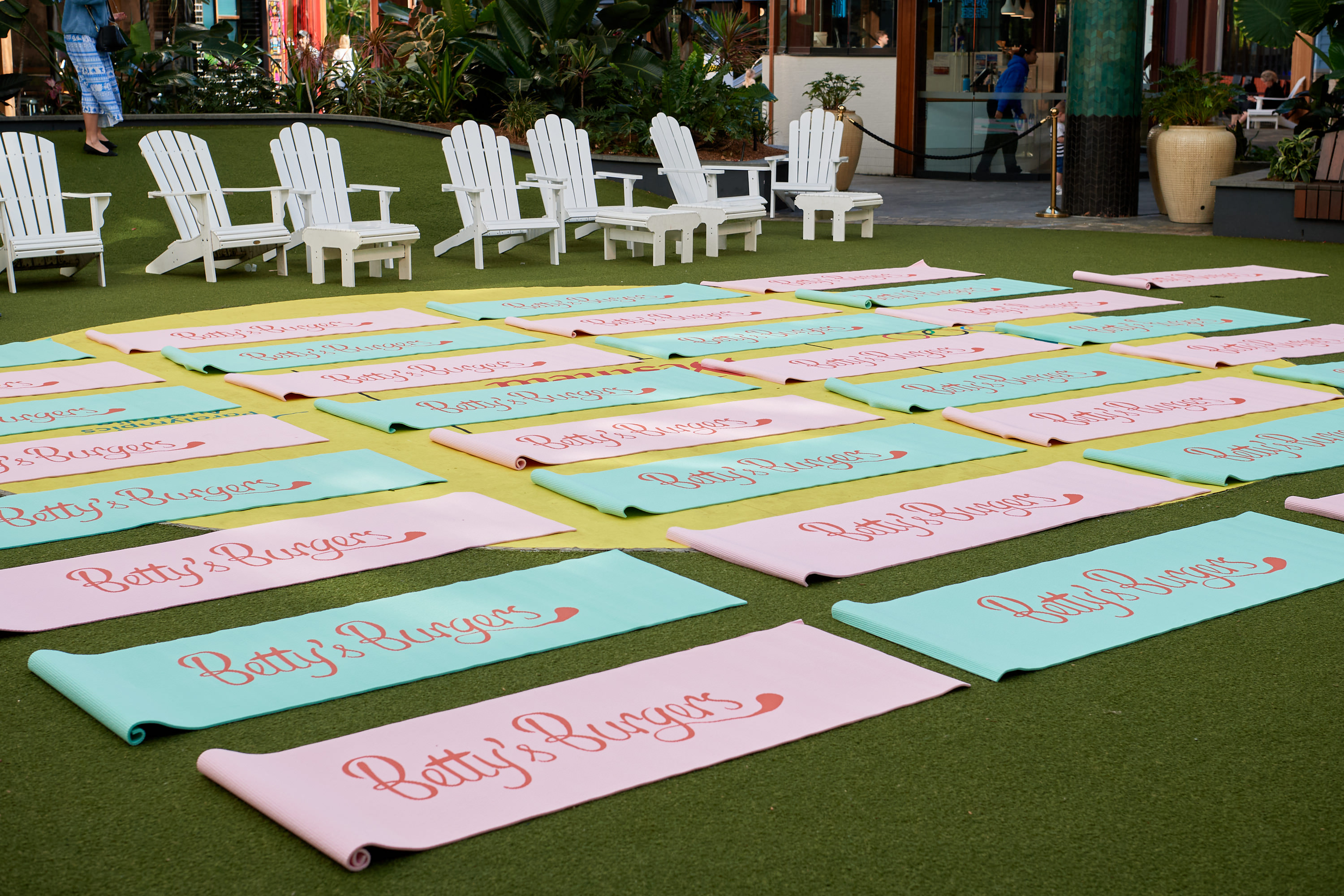 Rows of Betty’s Burgers branded Pilates mats laid out on the lawn