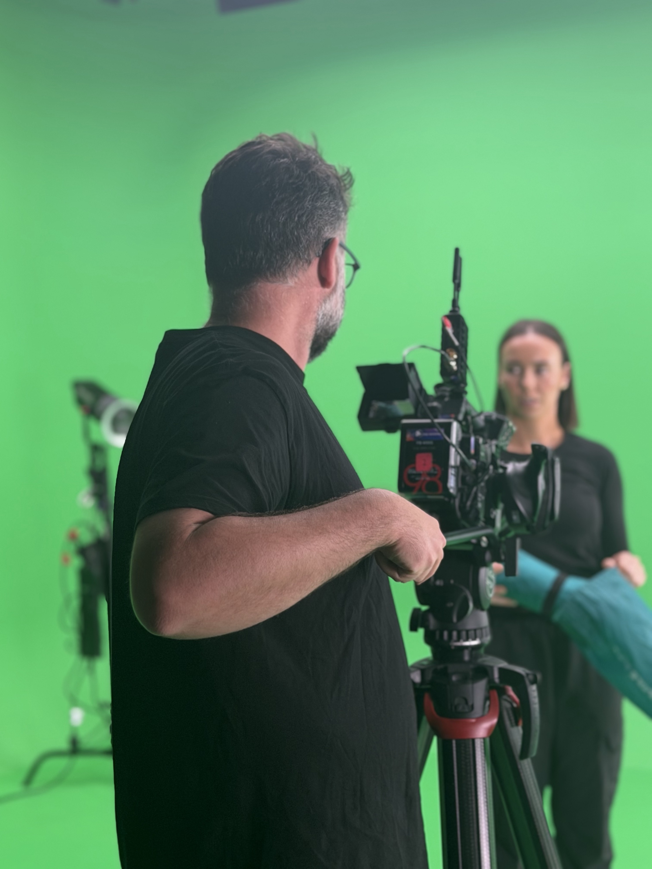 Camera operator filming talent on the green screen