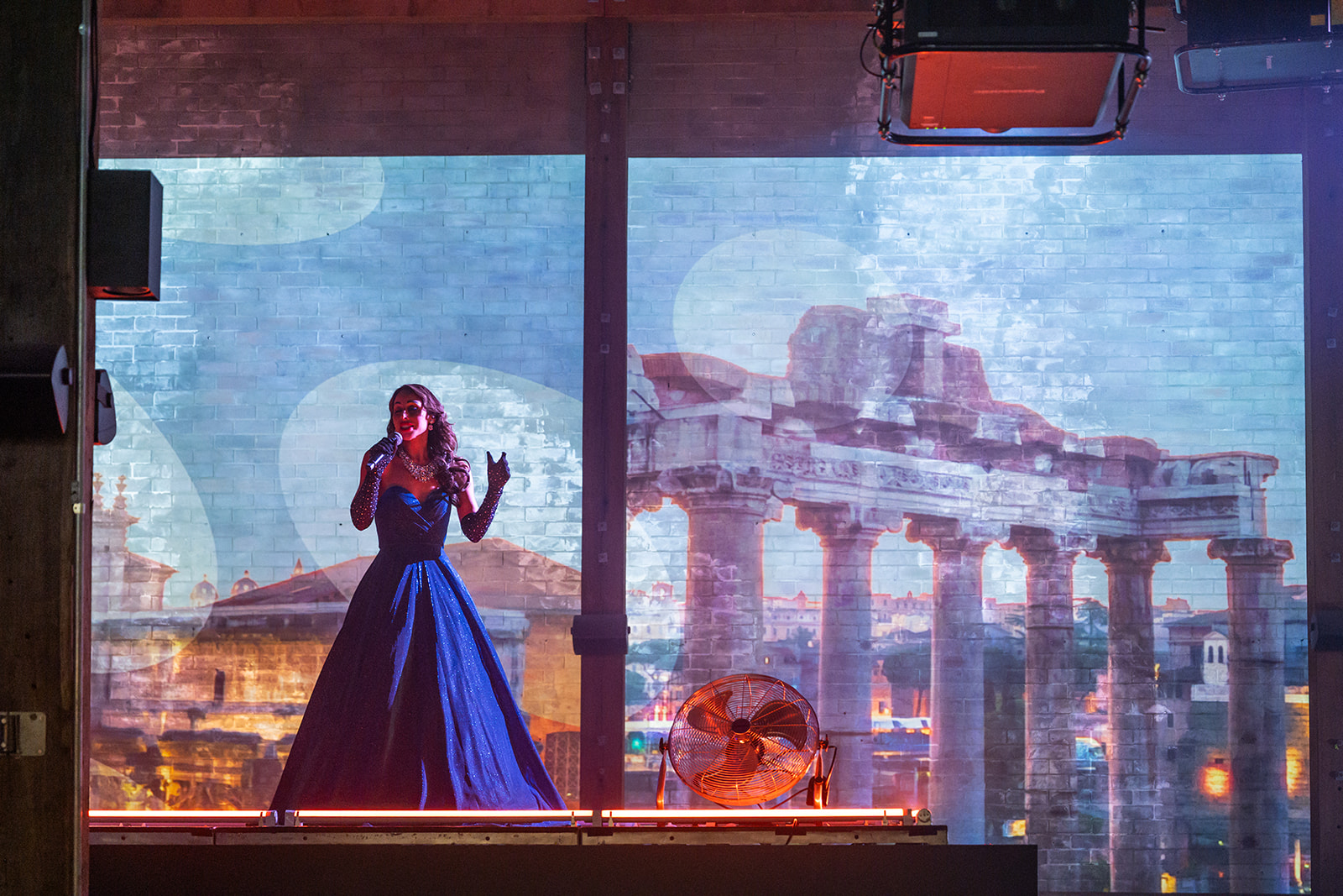 Singer performing in front of projected Roman ruins