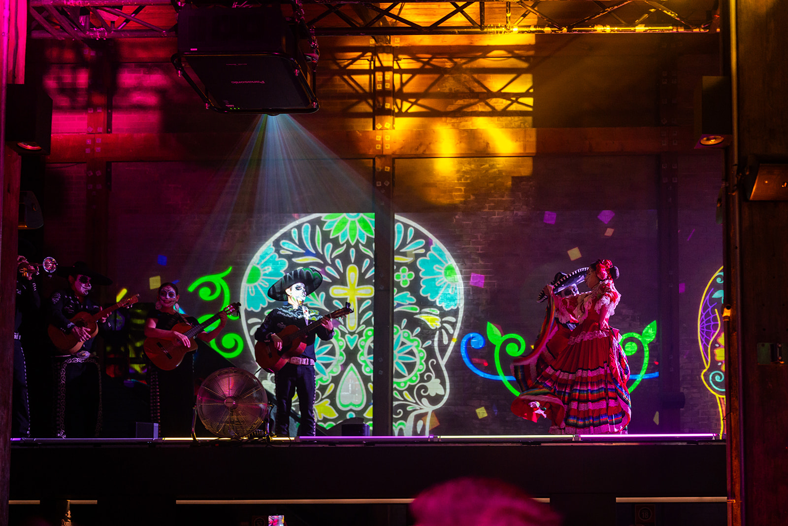 Day of the Dead performers in front of a projected sugar skull