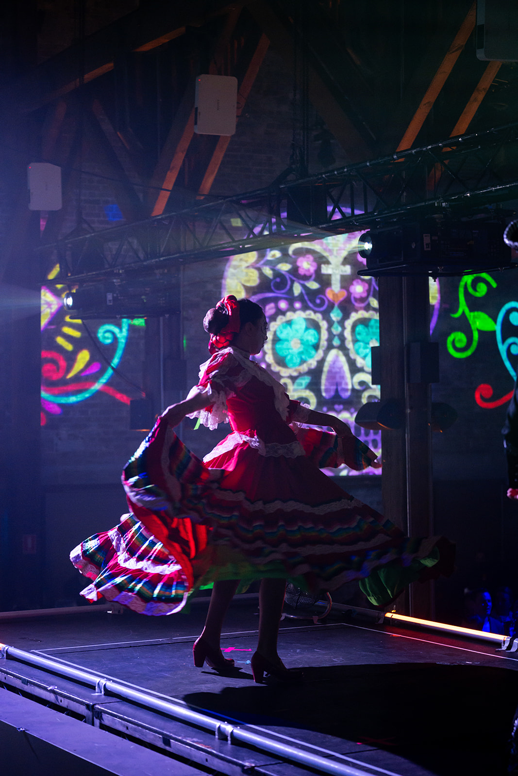 Dancer in a folk dress in front of a sugar skull projection