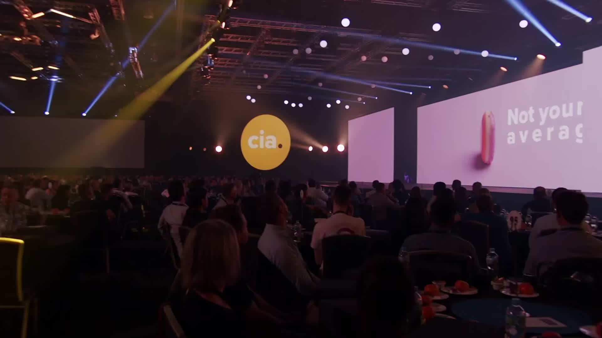 Audience at tables facing the CKO stage screens