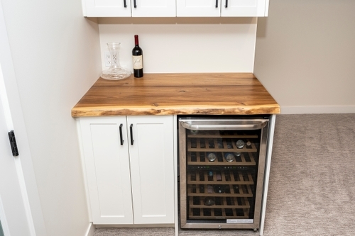 Custom wood bar top with wine fridge and cupboard underneath.