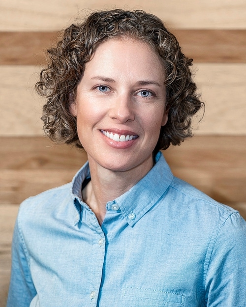 Headshot of a woman in a light blue button up shirt.