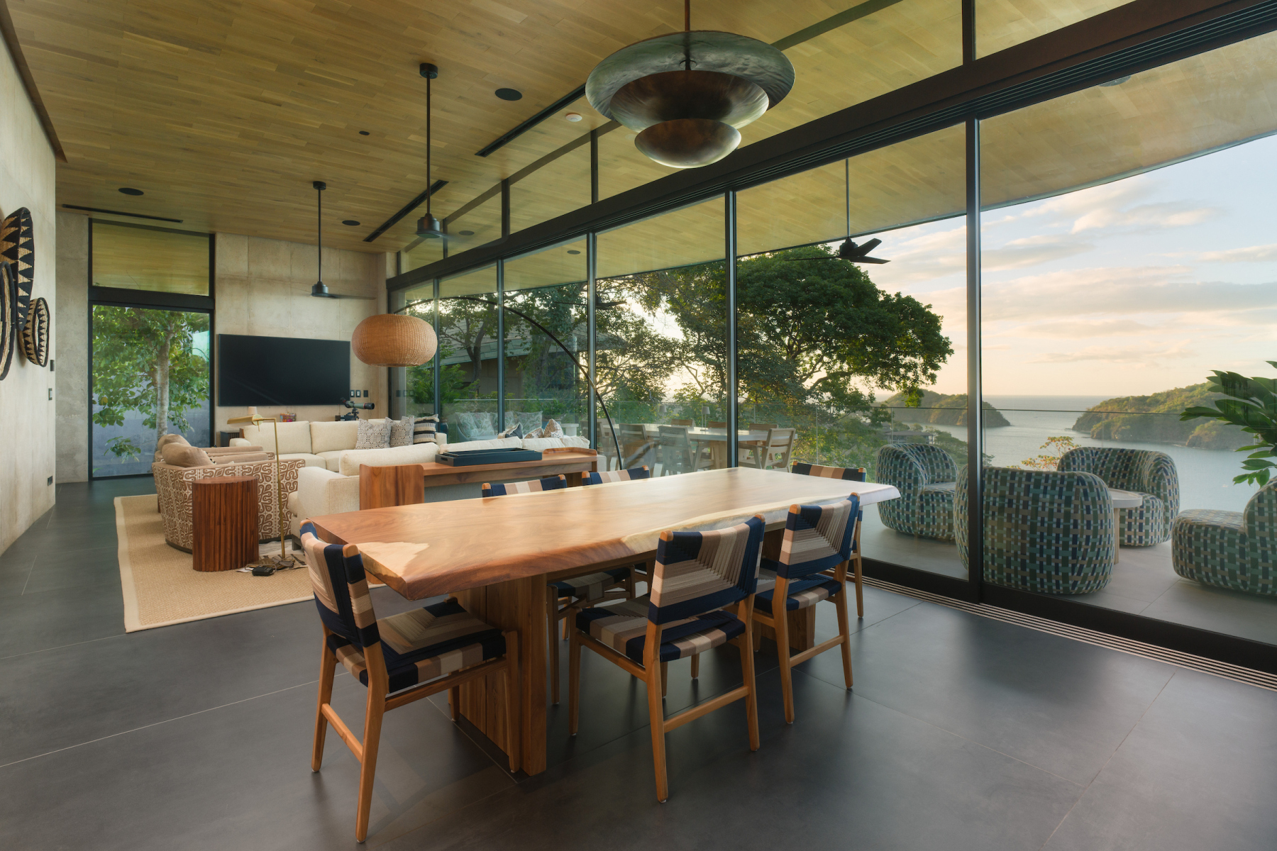 Wood dining table beside floor-to-ceiling windows overlooking the coast
