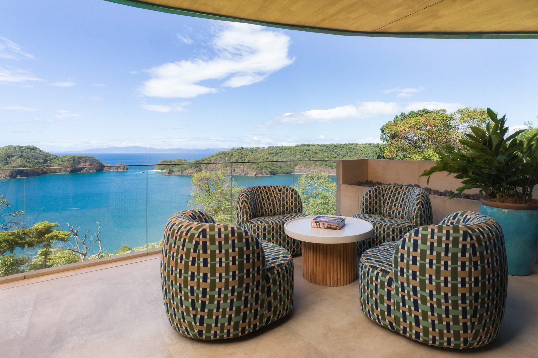 Woven terrace chairs overlooking a turquoise bay