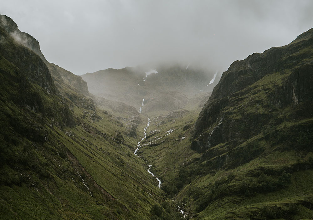 Landscape shot of a river flowing through a valley in the mist. 