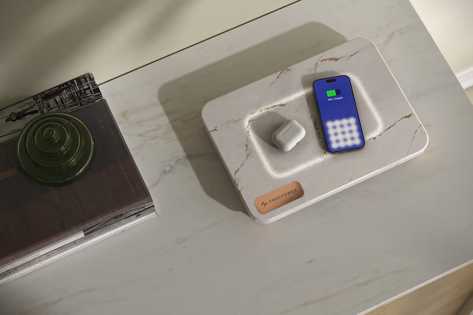 FreePower Valet - Wireless charging surface on a marble surface charging a smartphone and a pair of wireless earbuds.
