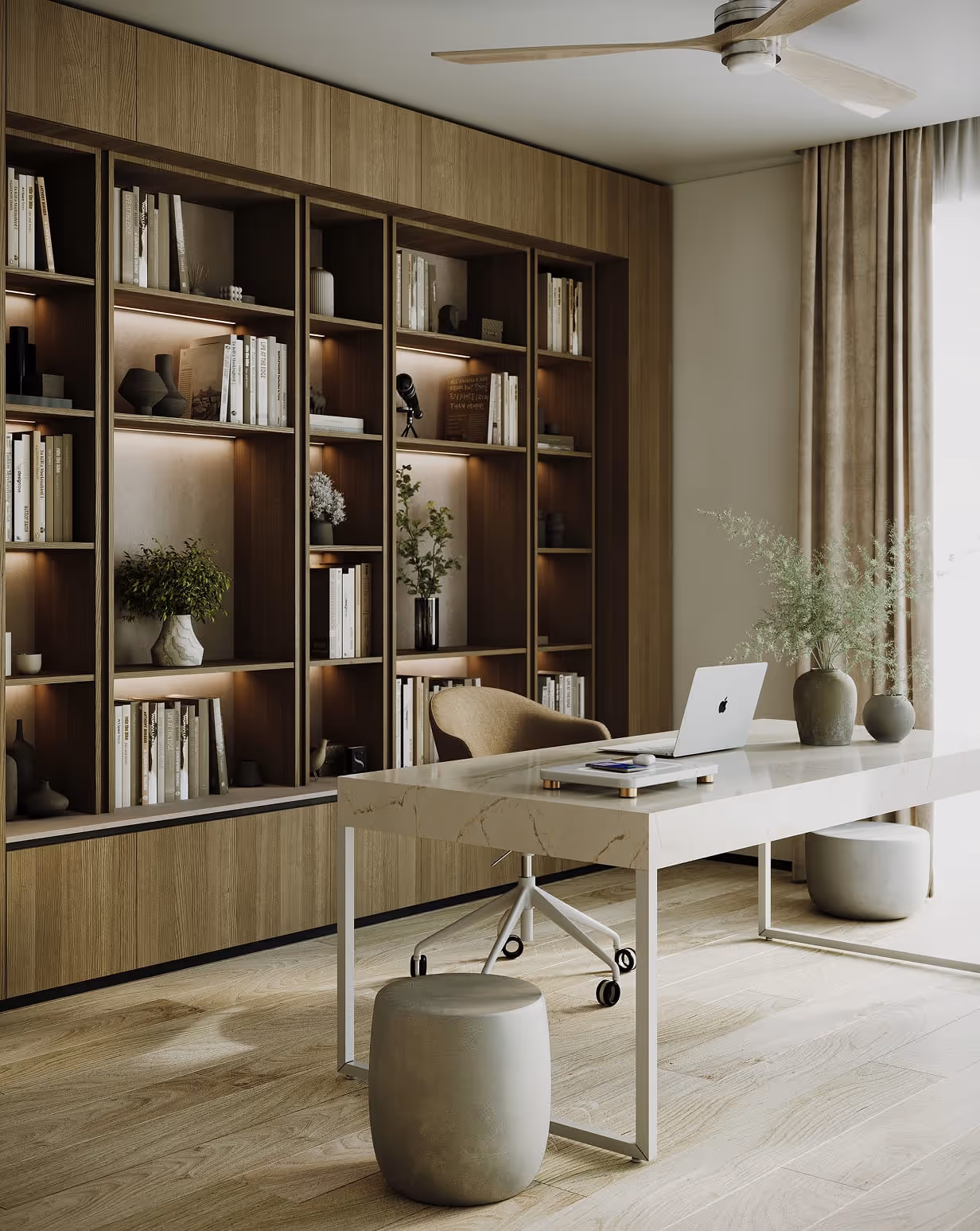 Modern home office with a light marble desk with a FreePower Valet wireless charging device on it, rolling chair, ottoman, large wooden bookshelf with books and plants, and a ceiling fan.