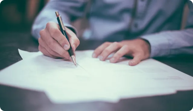 Hand unterschreibt ein Schriftstück, Sinnbild für das Vertragsrecht