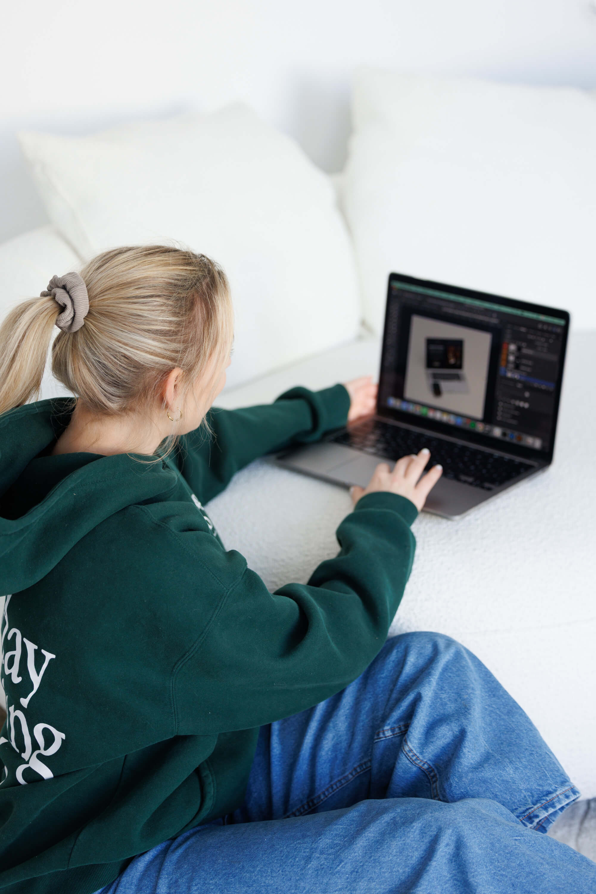 Tina Hörholdt von hinten am Laptop, auf dem Bildschirm ein Designentwurf