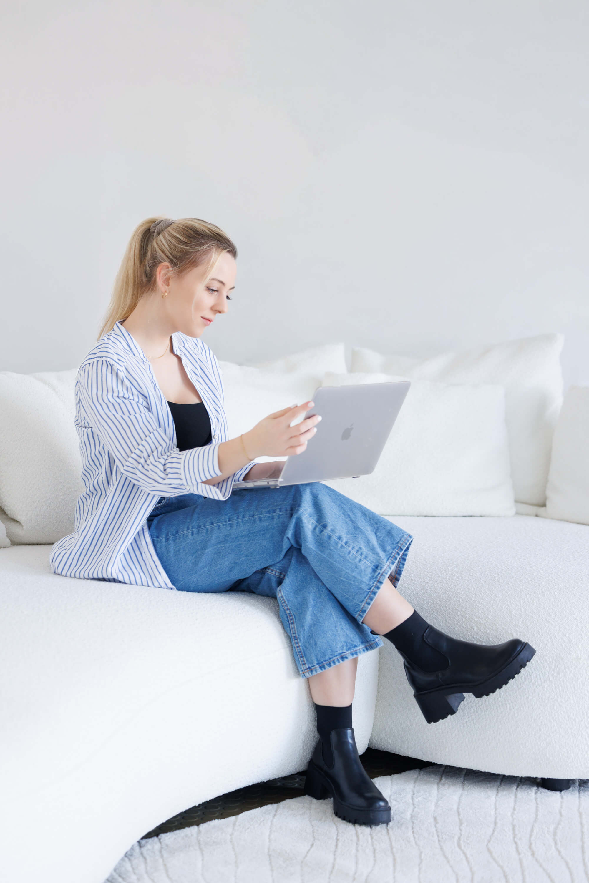 Tina Hörholdt sitting on a white sofa with her laptop