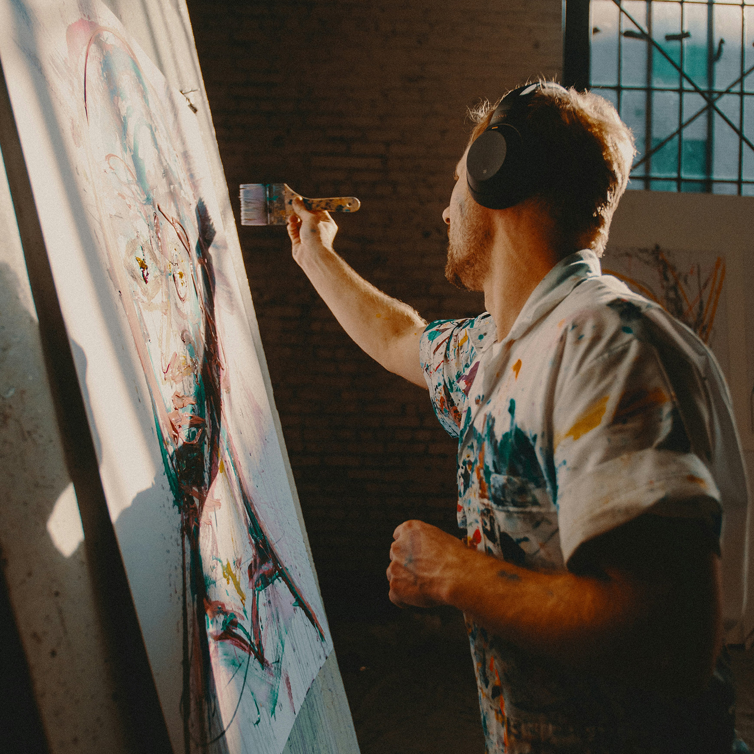 Artist with headphones painting on a large canvas