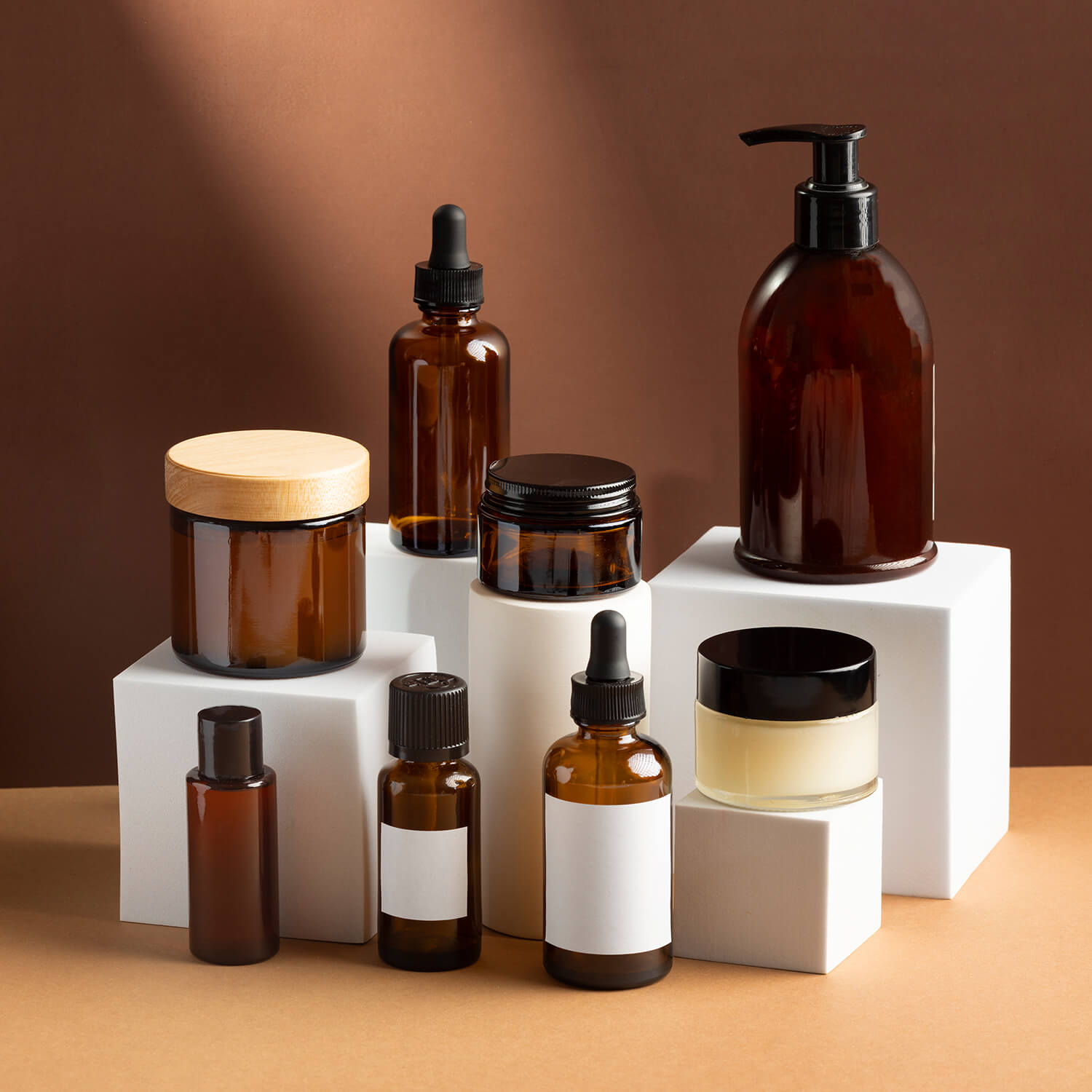 Amber glass cosmetic bottles and jars on white pedestals