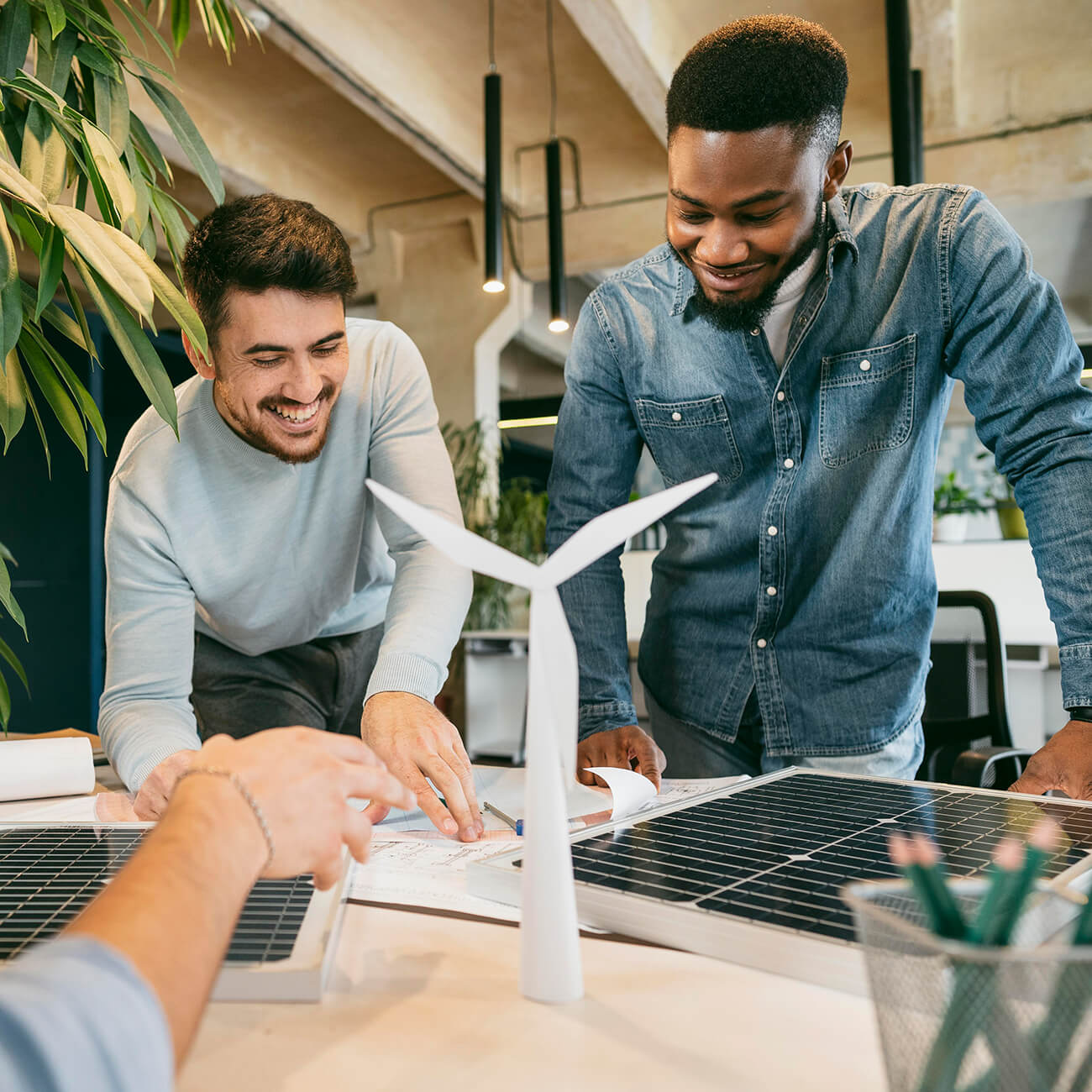 Two colleagues discussing a model with a wind turbine and solar panel