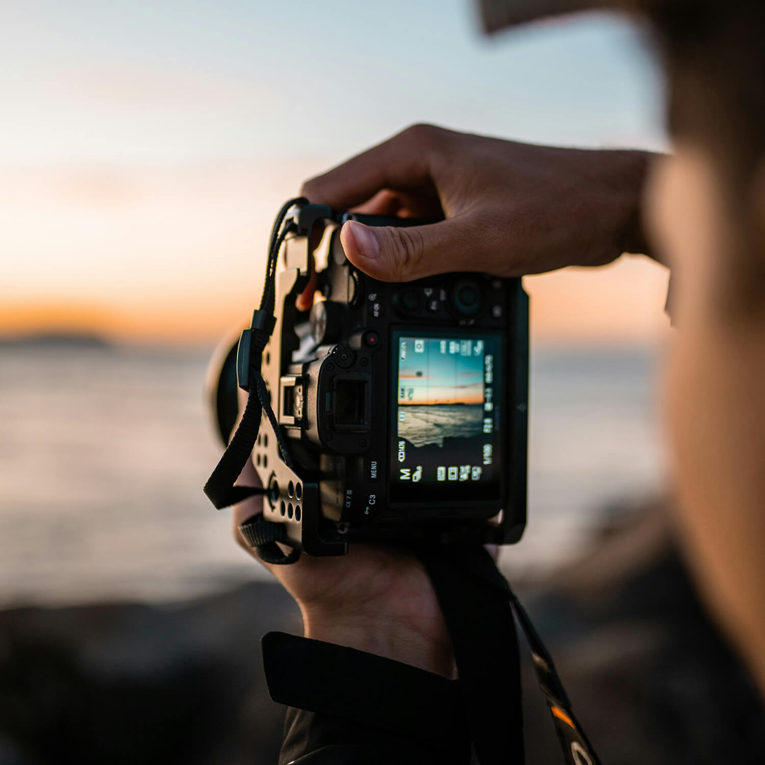Fotograf mit Kamera bei Sonnenuntergang am Meer
