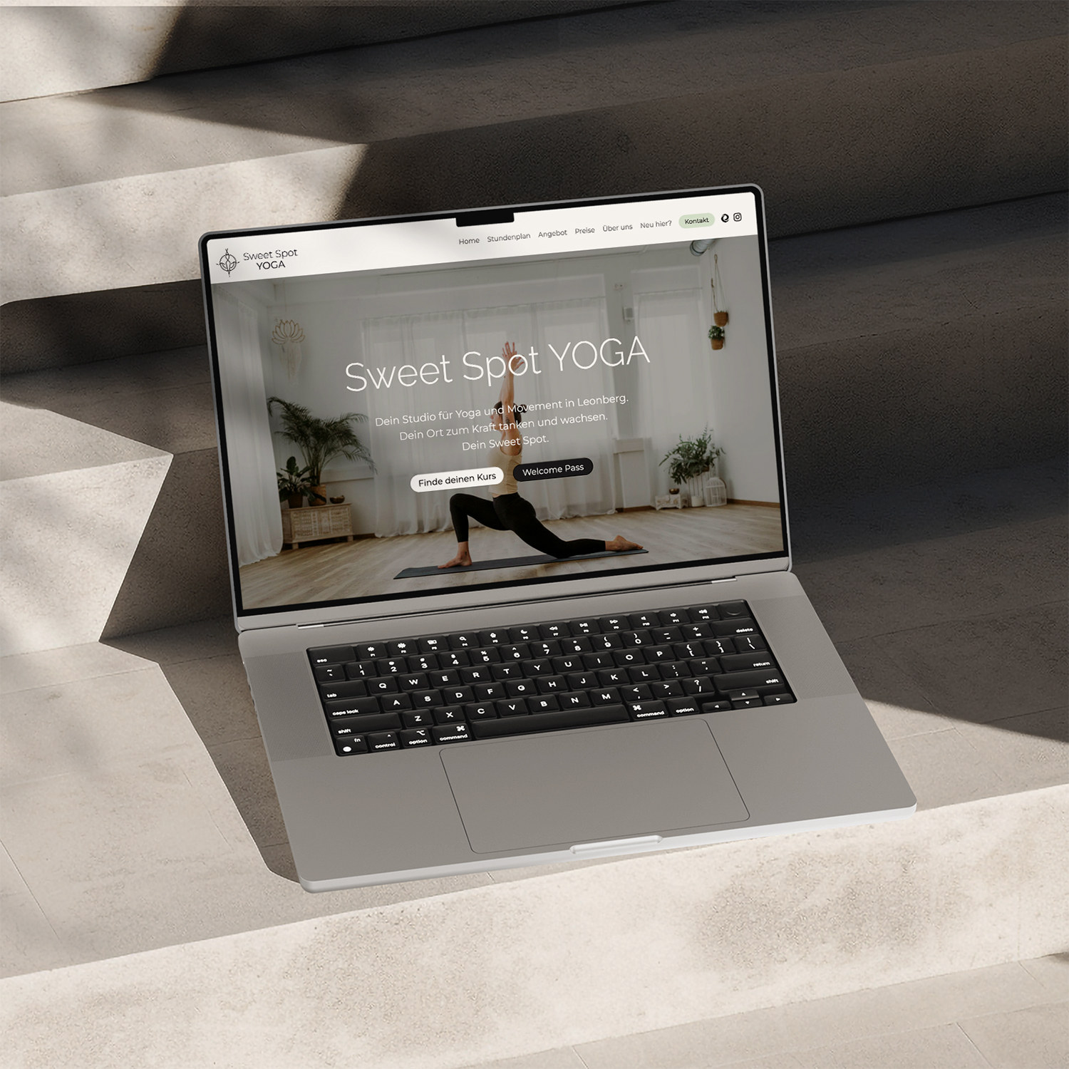 Laptop on stone steps showing the Sweet Spot Yoga website