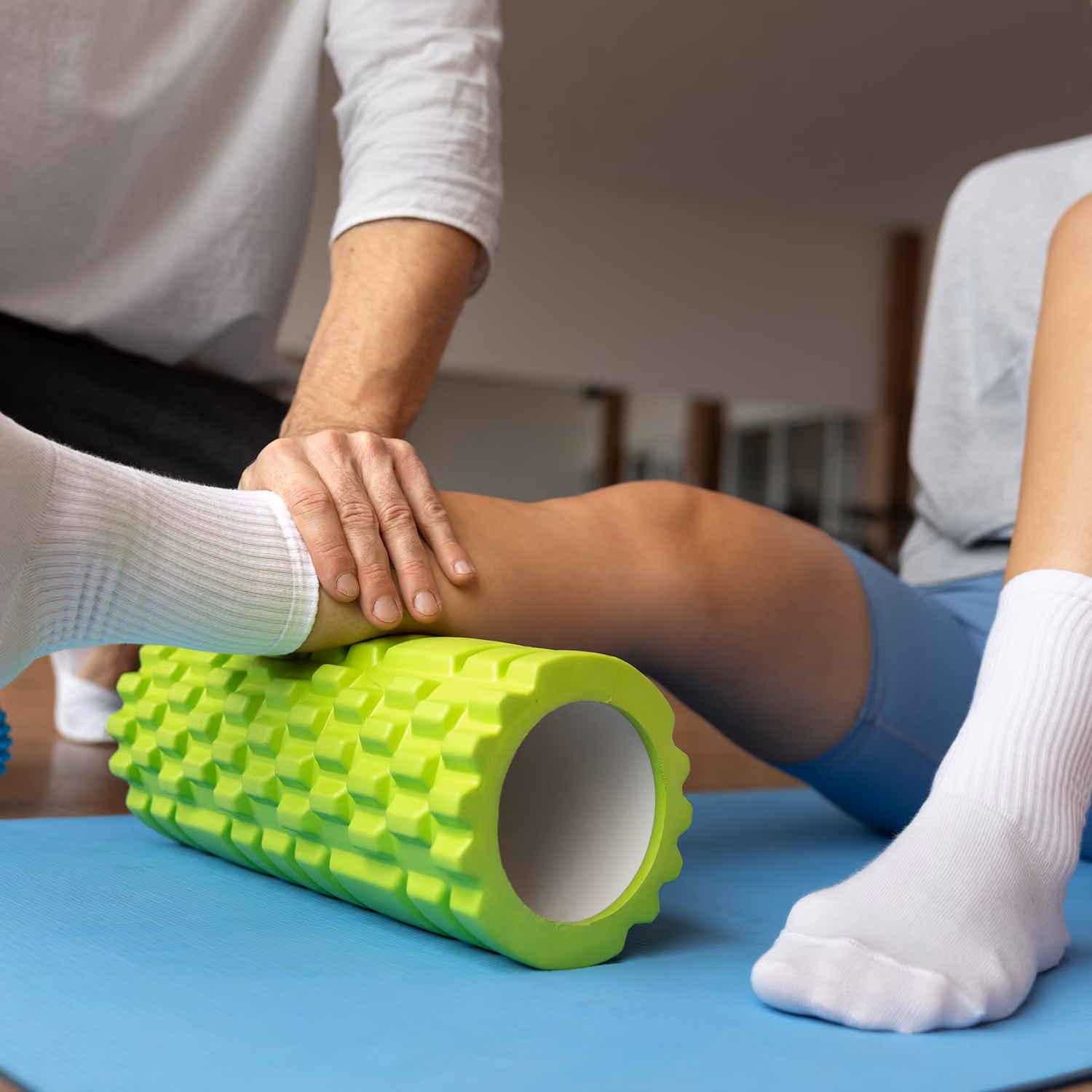 Physiotherapie: Ein Therapeut arbeitet mit einer Faszienrolle am Bein einer Patientin