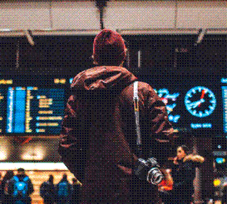 Person with camera strap looking at a large train station departure board and clock.