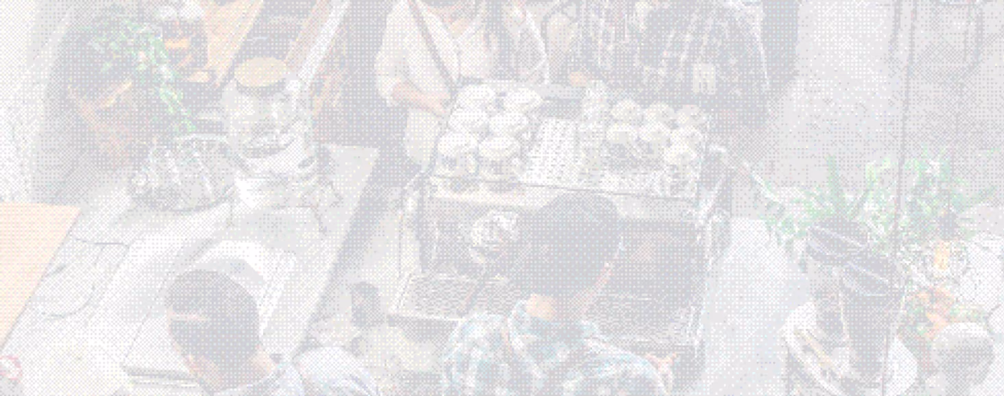 A busy market stall with a person selling eggs in trays to customers on a metal table.
