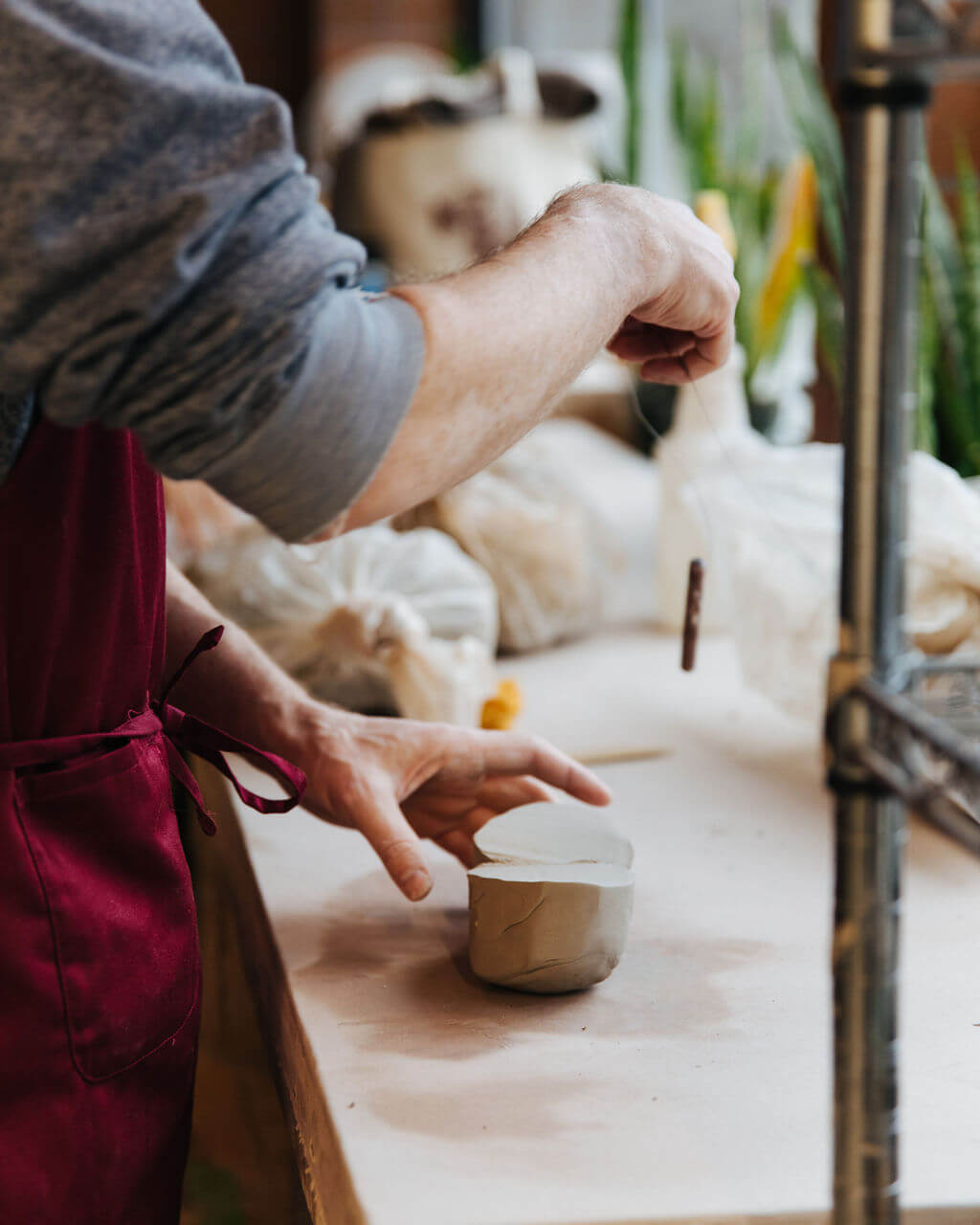 Hands trimming a small clay cup at Hand Eye Ceramics