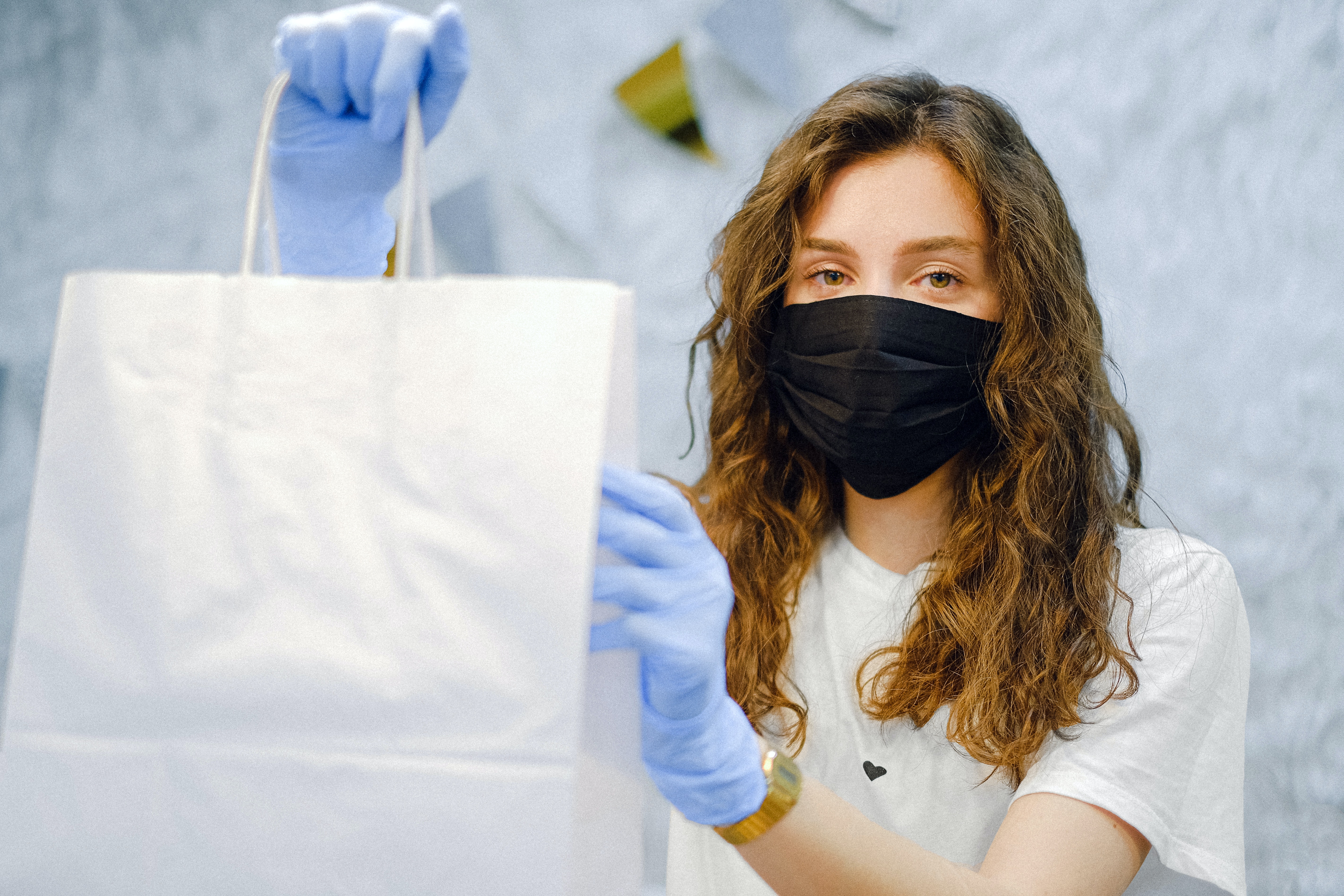 Masked worker handing over a paper shopping bag