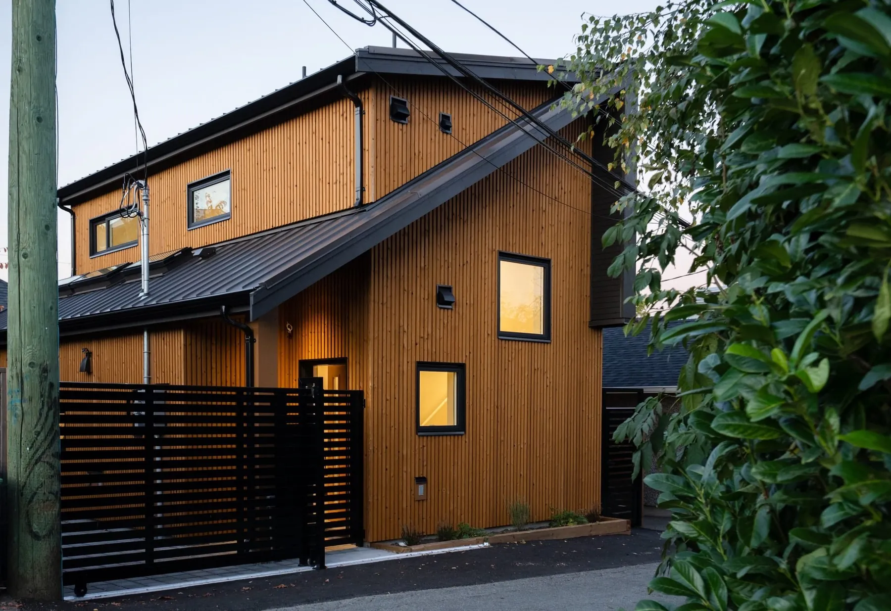 Cedar-clad laneway home at dusk by Smallworks